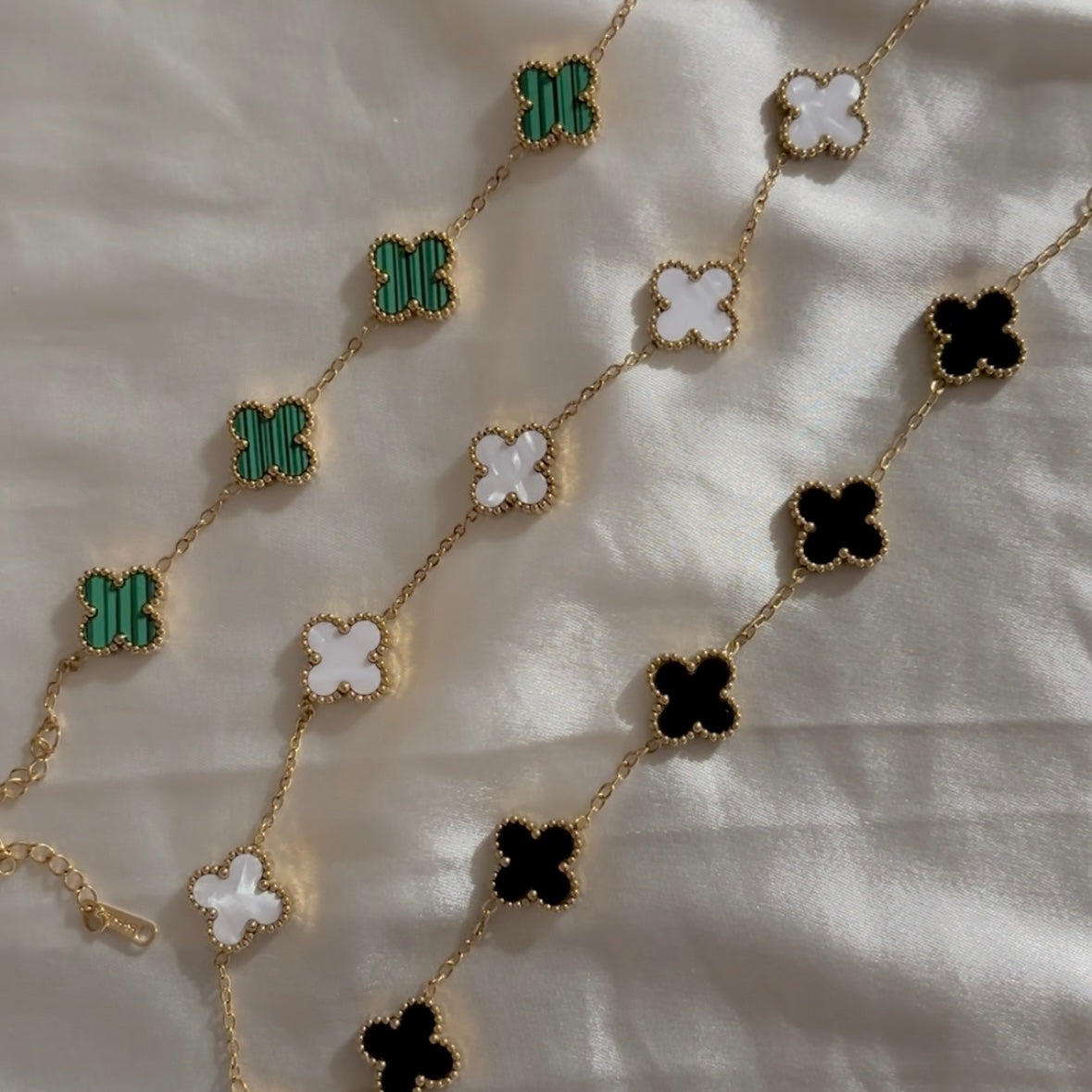 A gold-plated stainless steel bracelet with green clover-shaped charms jewellery in india